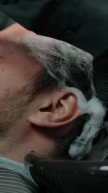 Berber dükkanında eldivenli şampuan köpüğüyle yıkanmış sakallı adam kafası. Profesyonel ve düzgün saç bakımı. Saç ve sakal kesiyorum. Dikey çekim.