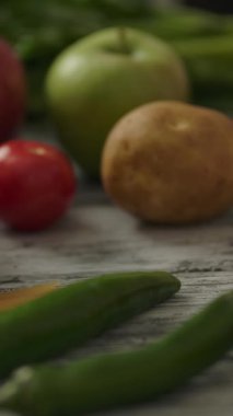 Kamera, taze sebzelerle dolu kereste masasını geçtikten sonra mutfaktan olgun domatesleri alan tanınmamış bir insana bakıyor. Dikey çekim.