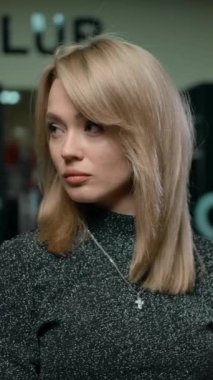 Modern berber dükkanında çalışırken sarışın çekici bir kadının kameraya doğru döndüğü görüntüsü. Ağır çekimde destansı bir portre. Dikey çekim.