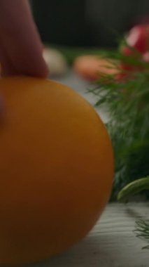 Tanımlanamayan biri tarafından çekilen taze portakal görüntüsü, sonra da ahşap mutfak masasının üzerinde olgun sebzelerin yanından uzaklaşan bir kamera. Dikey çekim.