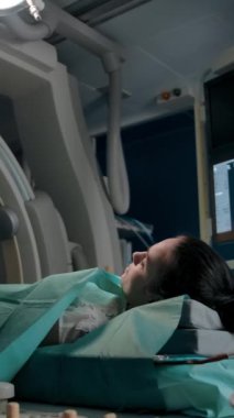 Cerrah modern ameliyathanede hastaya tavsiye eder. Yetişkin bir adamın, yatakta yatan genç bir bayanın yanındaki genel planı. Yavaş çekim. Dikey çekim.