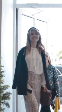 Yavaş çekimde çağdaş moda dükkanına girerken ve yürürken, moda kıyafetleri içinde mutlu genç kadınların ilgisini başka yöne çekiyor. Dikey çekim.