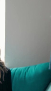 Kamera, modern mağazada kanepede otururken ve online alışveriş yaparken gülümseyen ve tabletteki online kataloğu tartışan şık kıyafetler içindeki mutlu genç kadınlara bırakıldı. Dikey çekim.