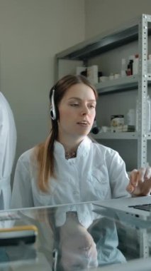 Kulaklık takmış kadın eczacı çalışanlara beyaz karton kutu içinde düzen sağlama görevi veriyor. İki meslektaş internetten müşteriyle sohbet ediyor. Pakete yeniden odaklanıyorum. Doli tava vuruşu