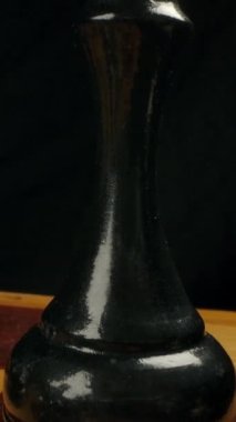 Satranç tahtasındaki siyah tahta bir satranç kralının yakın çekim makro resmi. Siyah beyaz satranç taşlarıyla dama tahtasının üstünde düzgün kamera hareketi. Siyah arka plan. Dikey çekim.