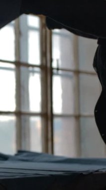 Tanımlanamayan kadın silueti, dokuma ustası, kesilmemiş bir parça süet kumaşı alır ve masaya serer, yavaş çekimde dikey çekime hazırlanmak için..