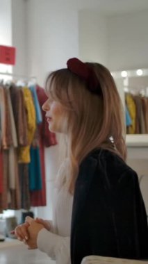 Yavaş çekim, modern moda bayan arkadaşlarının moda butiğinde sandalyelerde otururken konuşmaları ve tartışmaları. Dikey çekim.