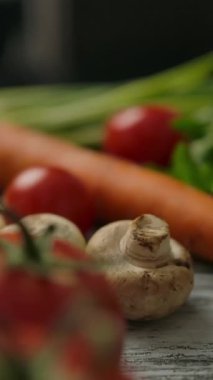 Yemek hazırlama sırasında mutfak masasında çeşitli olgun sebzeler ve spagetti ile hareket eden yakın çekim kamerası. Dikey çekim.