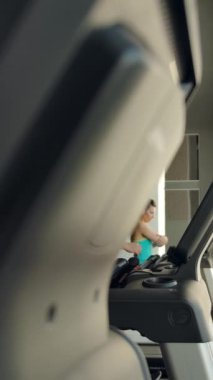 Modern spor salonunun içinde koşan sporcuların yavaş çekimleri. Güçlü sağlıklı sporcular kardiyo yapıyor. Dikey çekim.