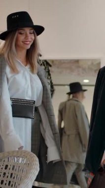 Çağdaş butik galerisine yavaş çekimde giderken şık giyinen ve gülümseyen muhteşem kadınların düşük açılı izleme çekimi. Dikey çekim.