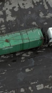 Araba vagonunun hava görüntüsü depoya boşaltmak için konteynır getiriyor. Birkaç farklı konteynır boşaltıldı ve özel inceleme için bekletiliyor. Dikey çekim.