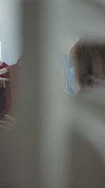 Moda mağazasında yeni kıyafet seçen ve güzel pembe elbiseler giyen genç ve şık bayan müşterilerin yavaş çekimleri. Dikey çekim.