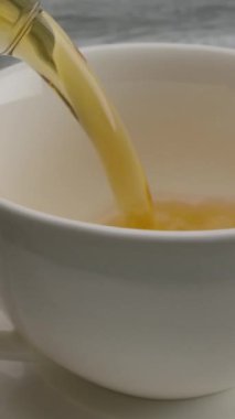 Çaydanlıktan yapılmış bir çay tabağının üzerine siyah çay dökmek. Dolly makro yavaş çekim kırmızı-kahverengi altın çay. Dikey çekim.
