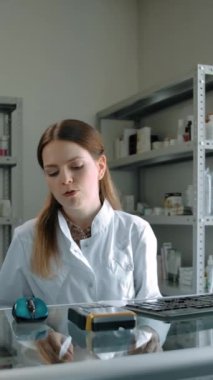 Kadın eczacı kredi kartı ödemesiyle alıcılar için ilaç hazırlıyor. Yetişkin beyaz erkek hapları, modern eczanede öksürük tozu. Profesyonel çalışan satıcısı. Dikey çekim.
