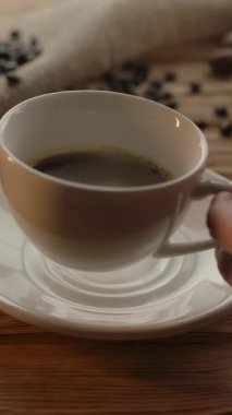 Kapuçino 'nun hazırlanmasına yakın plan. Masaya kurabiye ve kavrulmuş kahve çekirdekleri ile köpüklü süt eklenecek. Dikey çekim.