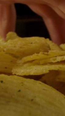 Kapalı kapılar ardında dönen kaseden bir sürü tırtıklı patates cipsi alan isimsiz biri. Dikey çekim.