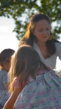 Genç bir anne ve iki küçük kızı yalnız bir meşe ağacının yakınındaki bir açıklıkta piknik yaptılar. Beyaz elbiseli güzel bir anne oyuncak tavşanı düzeltir ve en büyük kızına sunar. Dikey