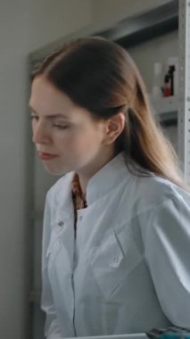 Kafkasyalı iki eczacının eczanenin içinde ilaçtan bahsettiği sahnenin ortası. Olgun bir adam, metinde tıbbi bilgiler gösteriyor. Genç, güzel bir kadın doktorla konuşuyor. Dikey çekim.