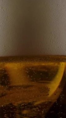 Taze bira bardağının geçmişteki akışına zum yapan kamera karanlık bir barda fokurdayan ve köpüren alkollü içecek kadehine dönüşüyor. Dikey çekim.