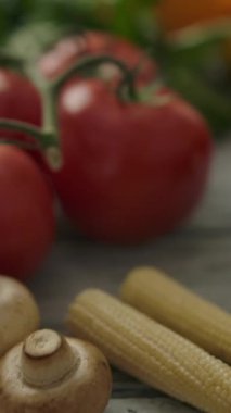 Kameralar doğal sebzeler ve yeşil otların üzerinden mutfaktaki sulu portakallara geçiyor. Vejetaryen konsepti. Dikey çekim.