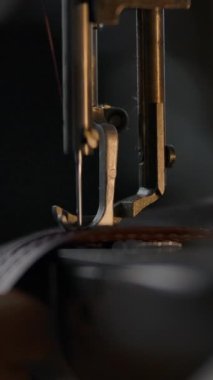 Dikiş makinesinin ayaklarına baskı yapan, yavaş dikişleri olan yakın çekim görüntüsü. Terziler el ele tutuşup deriyi dikkatlice dikiyorlar. El işi üretimi benzersiz bireysel çantalar, kemerler, aksesuarlar