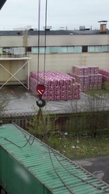 Bir otoyol vincinin kamyondan bir konteynırı boşaltırken çekilmiş görüntüsü. Eski konteynırlarla dolu küçük bir depo. Dikey çekim.