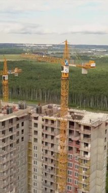 İnsansız hava aracı, yeni modern bina inşaatçılarının ve teknik ekipmanların üzerinde uçuyor. Çok katlı bir dairenin yüksek yüksekliği. Dikey çekim.