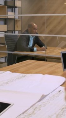 Takım aframerican ve beyaz bussines insanlar bir iş toplantı sırasında konuşurken boardroom bakarak bir cam pencereden ateş etti. Meslektaşlarının çizim ile ön planda. 4 k yavaş hareket