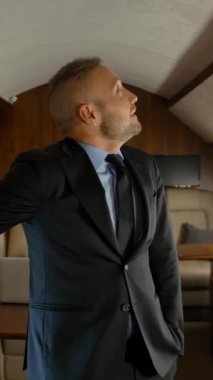 Özel jetiyle uçan bir iş adamı. Kendine güvenen yüz ifadesi. Girişimci, iş için jet kulübesine bakıyor. Dikey çekim.