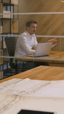 Genç yönetici modern ofis cam duvarları yönetim odasındaki evli çifte yeni bir ipotek anlaşması teklif ediyor. Yavaş çekim 4k Ultra HD geniş açı. Dikey çekim.