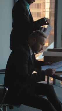 Girişimci, içinde dokümanlar ve yeni bir ofis bulunan bir karton kutuyu açıyor. Afro-Amerikalı patronu ona yardım etti. Yeni iş kavramı, yeni bir ofise taşınmak. 4k ağır çekim orta çekim. Dikey çekim.