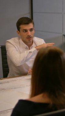 Video gözlüklü bir iş adamı. Modern cam ofiste inşaat ve yol çizimleri üzerinde çalışan bir grup genç müteahhit. 4K UHD odasında çeşitli iş adamları var. Orta atış. Dikey çekim.