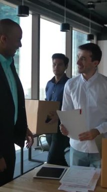 İş adamları, karışık ırklar yeni modern ofisin içinde eşyaları, belgeleri ve ekipmanları boşaltıyorlar. Güzel bir iş yeri manzarası olan büyük bir pencere. Ortadaki 4 km yavaş çekim. Dikey çekim.