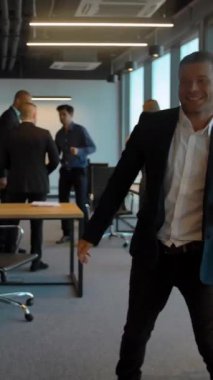 İş yerindeki çift kutlamayı kazandıktan sonra dans ediyor. Modern ofis binasında eğlenen iki beyaz erkek ve kadın. 4K Ultra HD. Dikey çekim.