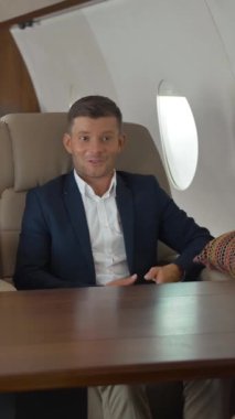 İş adamları özel jet koltuklarında iş konuşuyorlar. Kendine güvenen iki iş adamı ve çekici iş kadını küçük özel uçak kulübesinde çok zaman geçiriyorlar. Dikey çekim.