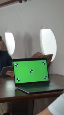 İş adamlarının şirket jetinde toplantıları var. Yeşil ekran dizüstü bilgisayar monitörünü izlemek için hazır. İki iş adamı ve iş kadını tartışıyor. Geniş açı. Dikey çekim.
