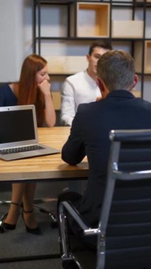 Adam ve karısı banka yönetim kurulunda avukatla konuşuyor. Modern cam duvar iş merkezi. İpotek belgelerini imzalıyorum. Dikey çekim.