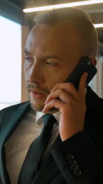 İş yerindeki iş adamının portresi anlaşma ortağına sesleniyor. Önemli bir cep telefonu görüşmesi, ciddi bir iş konsepti. Ağır çekimde yakın çekim. Dikey çekim.