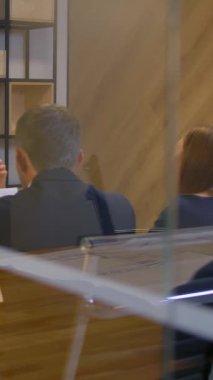 Çekici kendine güvenen yönetici modern ofis cam duvar yönetim odasındaki evli çifte ipotek sözleşmesi teklif ediyor. Yavaş çekim 4K çekimi. Dikey çekim.