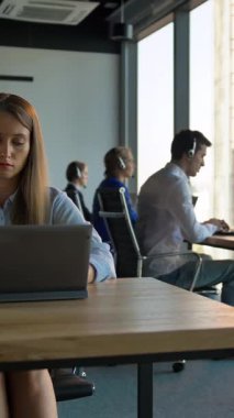 İşkadını patronunun portresi. İş yerindeki çağrı merkezini tutuyor. Kendine güvenen ve zeki bir yöneticiye benziyor. Kameraya bakarken gülümsüyor. Kaydırma kamerası hareketi. Dikey çekim.