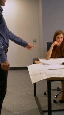 İspanyol çekici adam meslektaşlarına modern dokunmatik ped getiriyor. Masada yol çizimine bakıyorlar. 4k Ultra HD ağır çekim. Dikey çekim.