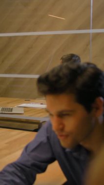 İş adamları anlaşmayı modern ofis içinde akşam saatlerinde tartışırlar. Kapalı özel konuşma. Dikey çekim.