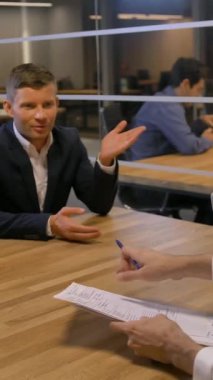 Çekici iş adamları toplantı odasında toplanıyor. Evli genç çift kârlı bir ipotek sözleşmesi imzalamak istiyor. 4k Ağır çekim. Dikey çekim.