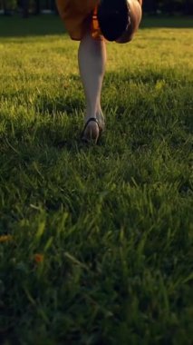 Yeşil çimlerde, park alanında koşan mutlu genç kadınlar. Çimenlerde koşan çapraz bacaklı bir kadın. Süper yavaş çekim. Dikey çekim.