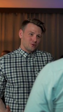 İki gülümseyen erkek ev partisinde konuşuyor. Şampanya içiyorlar. Orta UltraHD 4k Yavaş çekim. İyi iş, kadınlar, şarap, temalar. Rahat ol. Toplumsal dikey çekim.