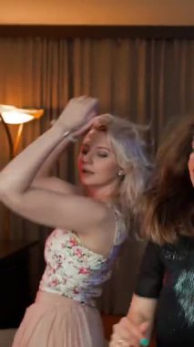 Partide üç gülen kız birlikte dans ediyor. Cuma partinin iyi bitmesi dileğiyle. Sadece dans, başka bir şey değil. Düşüncesiz zevk ve dikkatsizlik sadece dans eder. Dikey çekim.