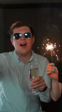 Bir grup arkadaşın havai fişeklerle eğlendiğine dair POV görüşü. Tatilin ve kameraya gülümsemenin mutluluğu. Dikey çekim.