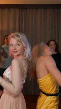 Partide arkada arkadaşlarıyla dans eden iki çekici seksi kız. Masa ve kanepede rahat bir ev. Doğum günü partisi patlağı. Yavaş çekim 4k Ultra HD. Stüdyo ekipmanı ışıklandırma renkli. Dikey