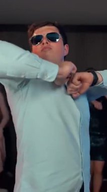 Çekici beyaz erkek dansçı ve partide gülüyor. Arka planda dans eden insanlar. Kapalı alanda. Gerçek zamanlı ile süper yavaş çekim karışımı. Parti konseptinde büyük bir patlama. Dikey çekim.
