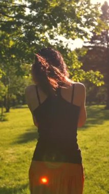 Çekici, güzel, kızıl saçlı, uzun saçlı, kulaklıklı müzikten hoşlanan, parkta koşan bir kız. Dikey çekim.